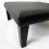 Large square black grained leather footstool with tapered black leg and studding